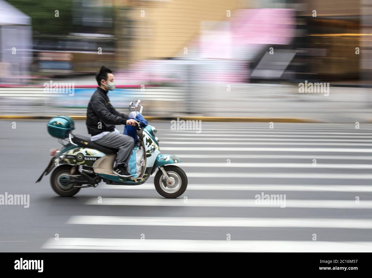 Man riding a scooter in Shanghai, China Stock Photo