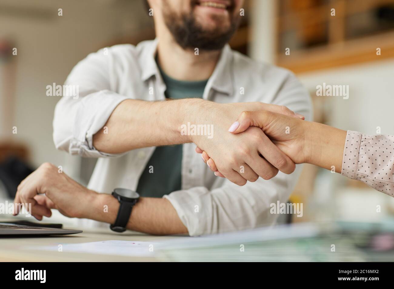Close Up Of Smiling Bearded Man Shaking Hands With Colleague In Minimal Office Setting Copy