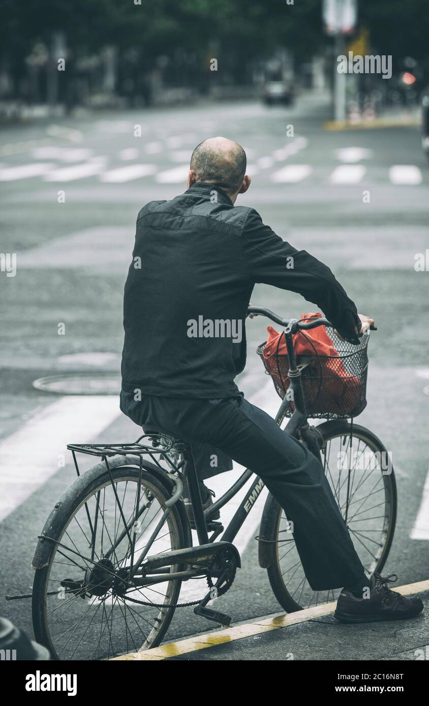 Man riding a bike on the streets of Shanghai, China Stock Photo