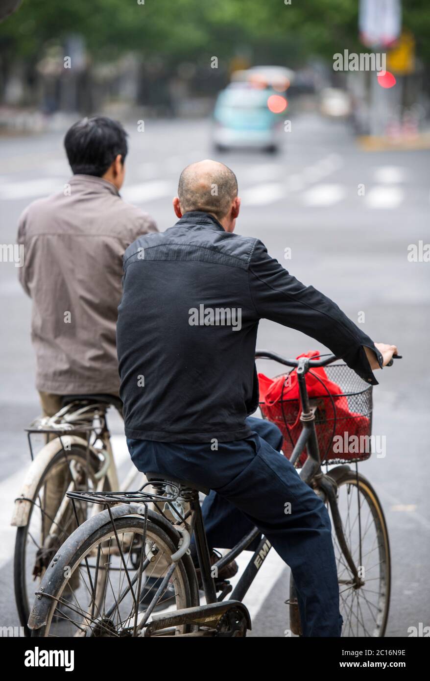 Men riding bikes on the streets of Shanghai, China Stock Photo
