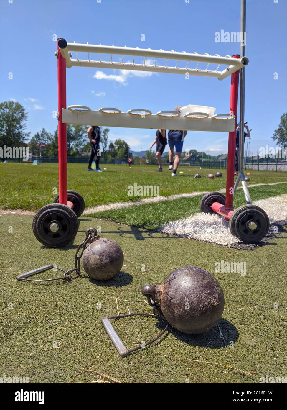 Weight throw implements with athletes in the background preparing to throw them Stock Photo