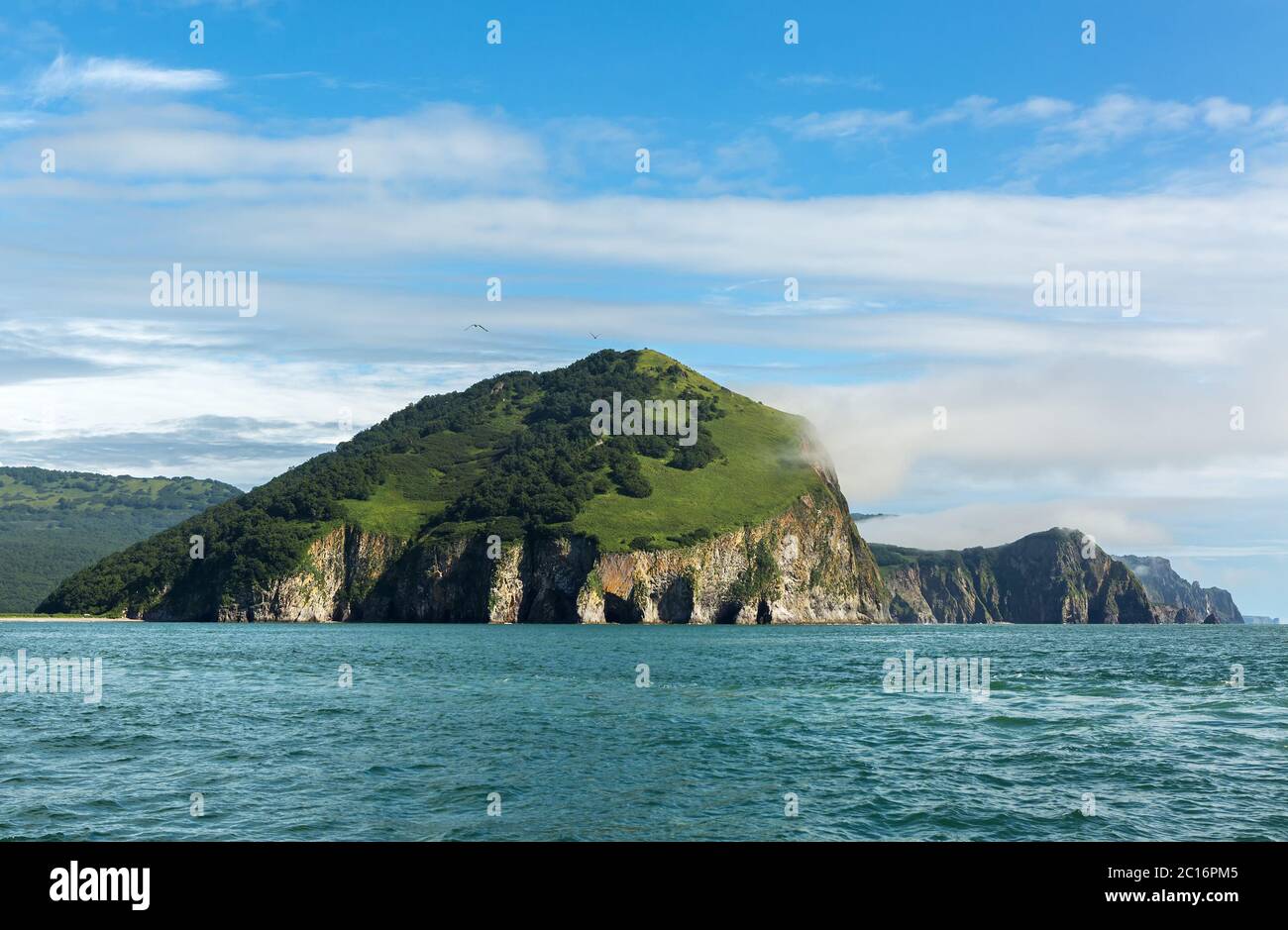 Rocks with caves and grottoes in Avacha Bay of Pacific Ocean. The coast of Kamchatka. Stock Photo