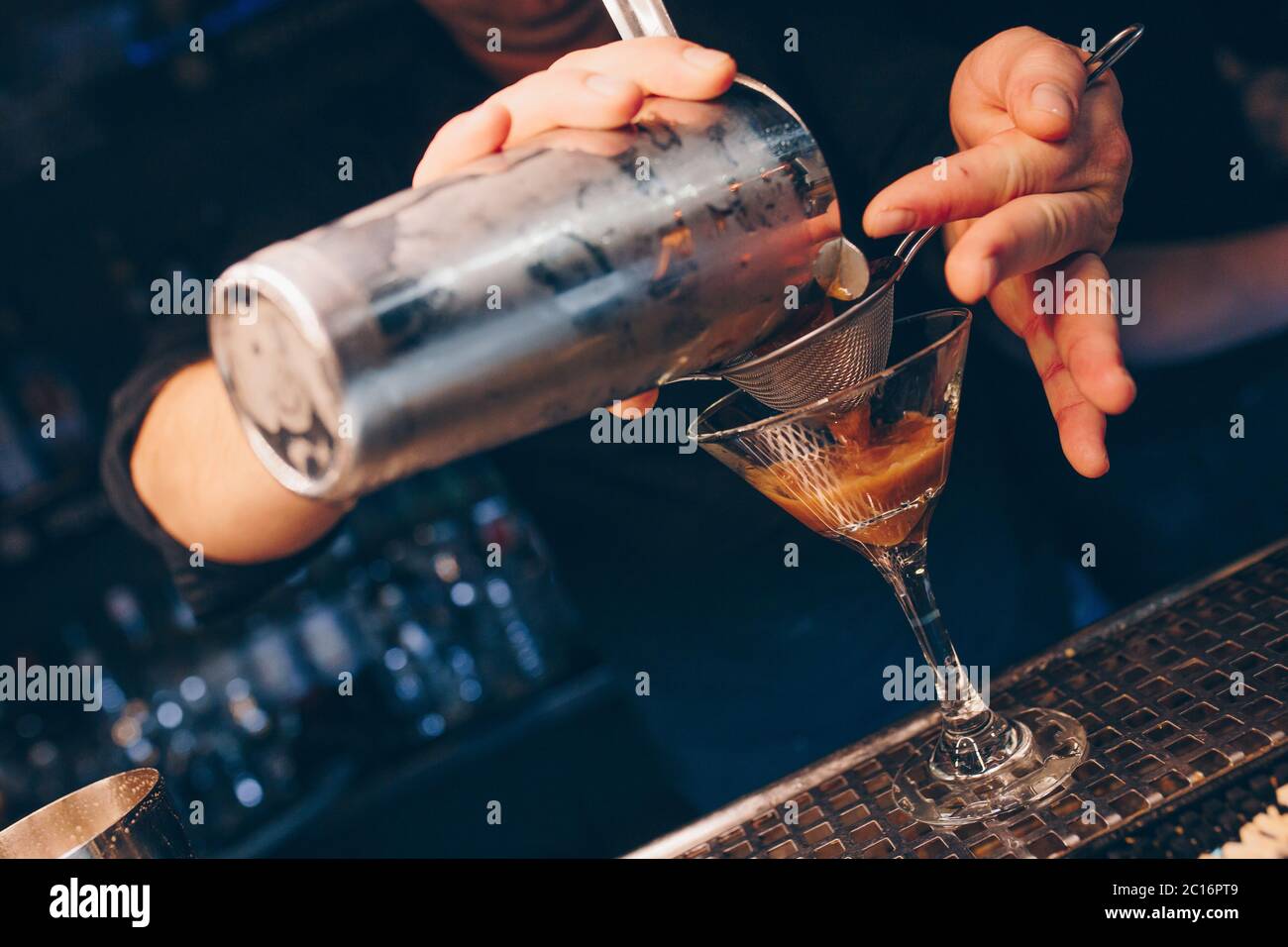 Bartender pouring using strainer White healthy Cocktail drink on a bar