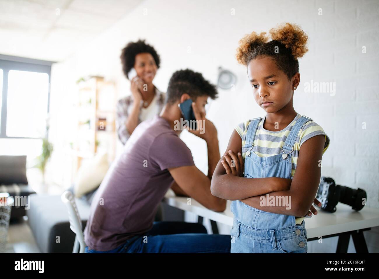 Frustrated sad child looking for attention from busy working parents Stock Photo