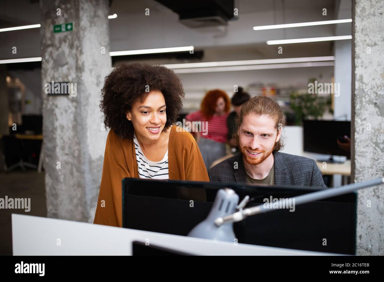 Working together on project. Happy young business colleagues working in ...