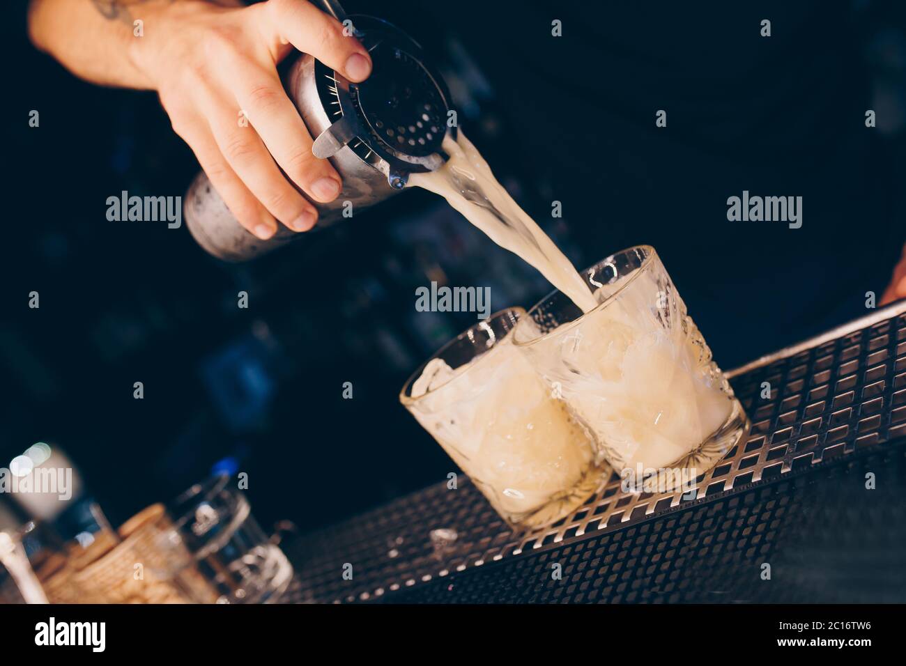 Bartender pouring using strainer White healthy Cocktail drink on a bar