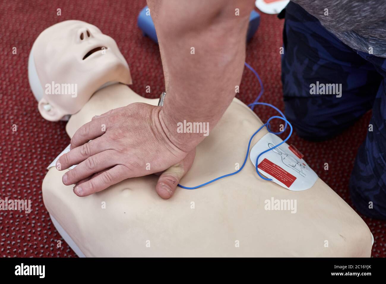 Male instructor teaching cardiopulmonary resuscitation with CPR dummy Stock Photo