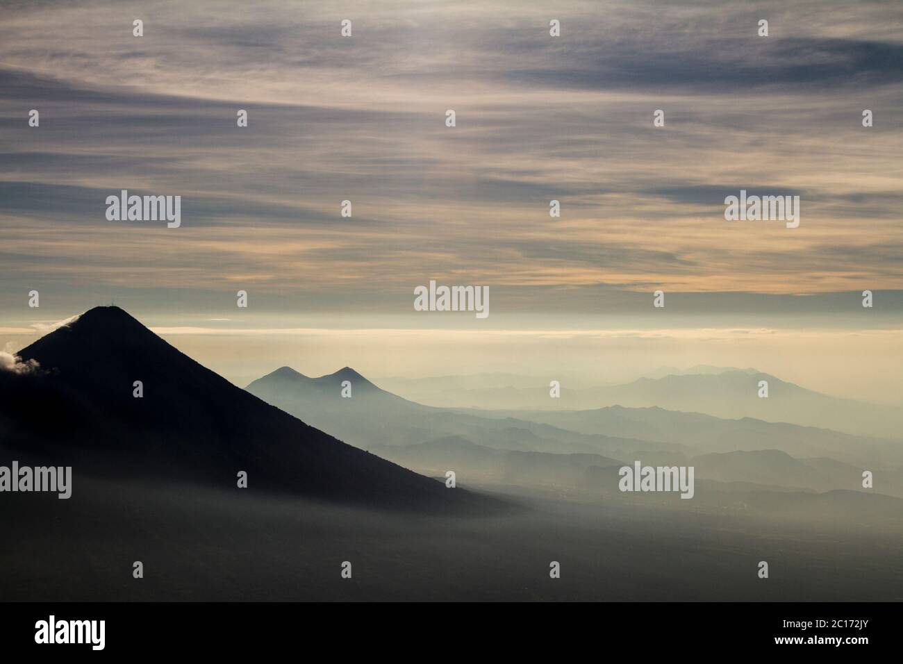 View of mountains and volcanos down a valley from Acatenango volcano during sunrise - Stock Image