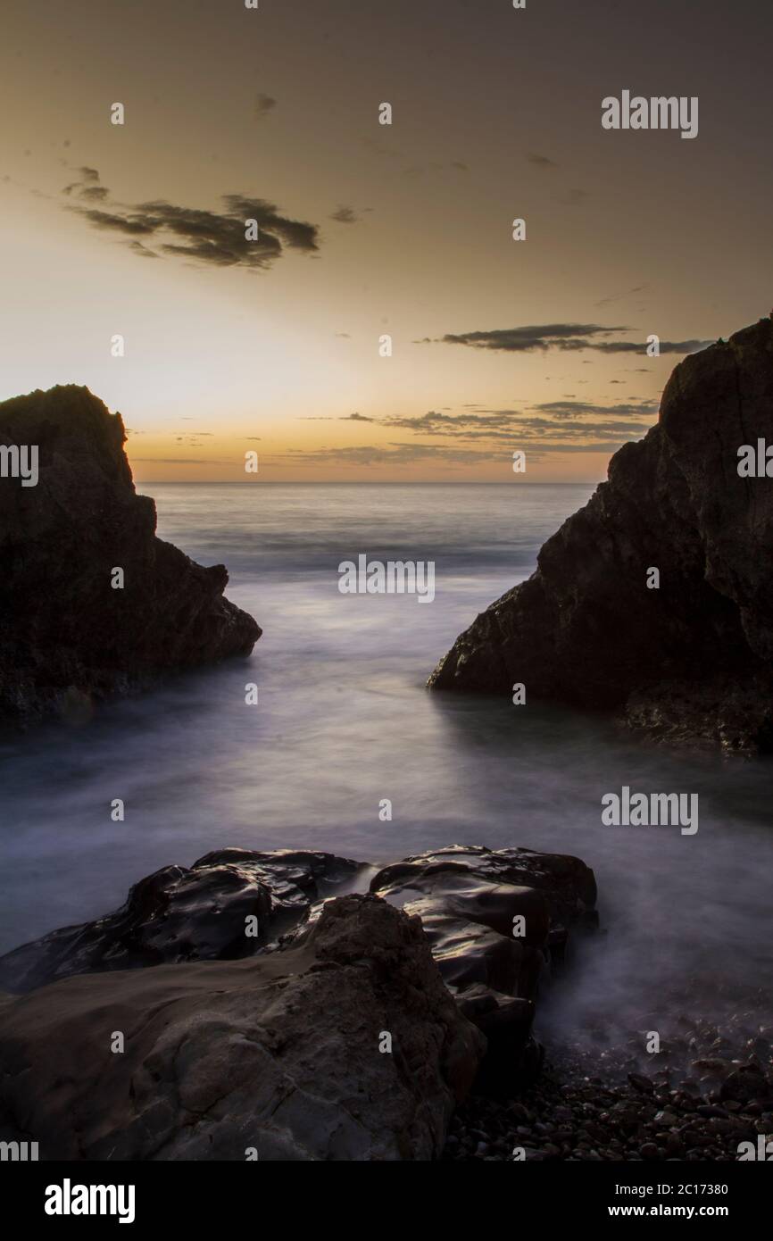 Slow exposure shot between rocks on Playa Coyote, Nicoya Peninsula, Costa Rica. - Stock Image