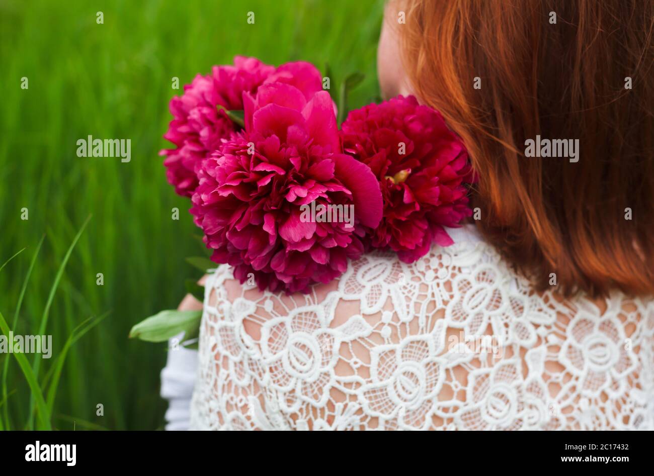 Girl with peony bouquet in the grass closeup Stock Photo