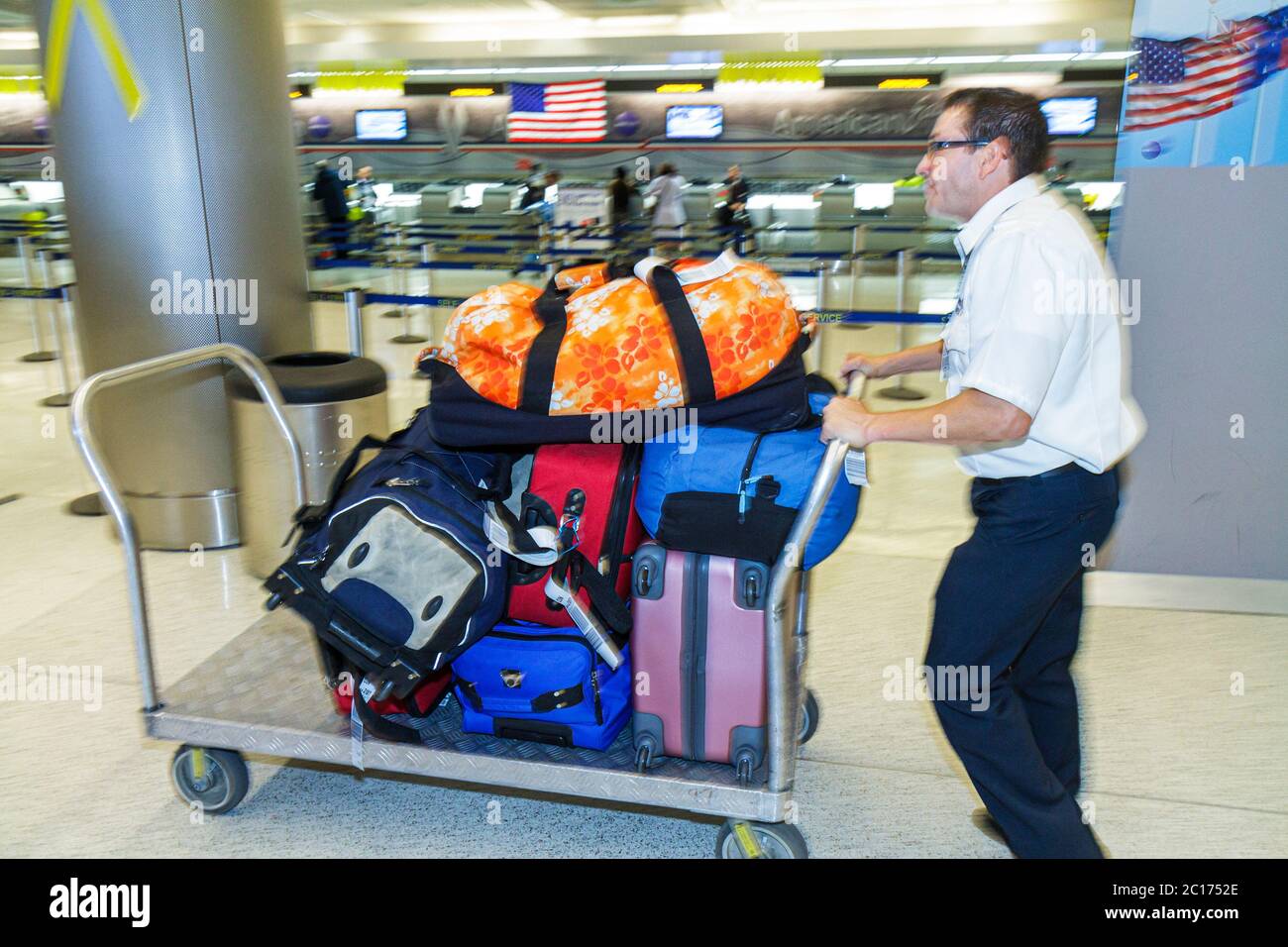 Miami Florida International Airport MIA,aviation,terminal,luggage,suitcase,baggage,stack,cart,carrier,man men male adult adults,pushing,working,work,s Stock Photo
