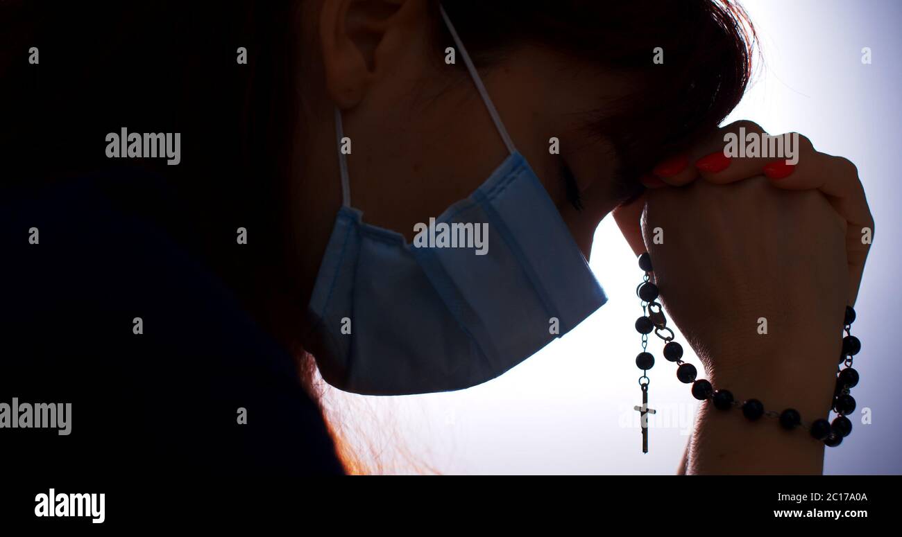 COVID-19 Concept. Silhouette of a woman hand praying, close up Stock Photo
