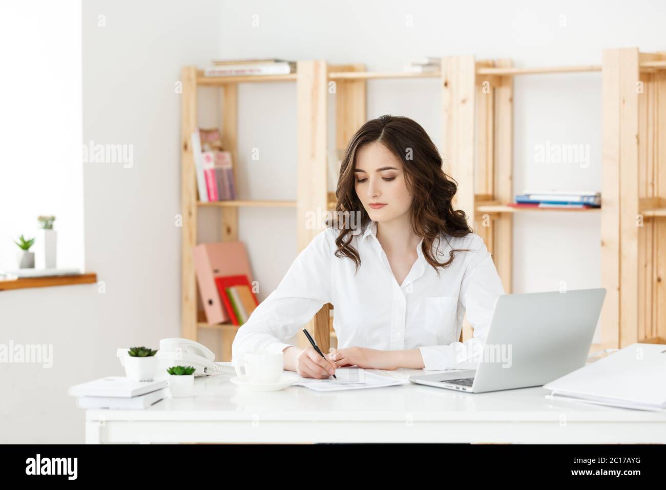 Young attractive woman at a modern office desk, working with laptop and ...