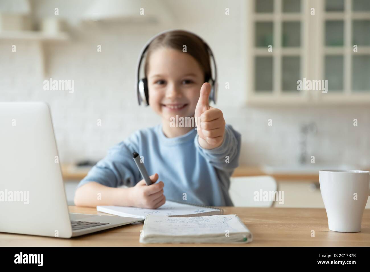 Closeup focus on thumbsup of little girl learning at home Stock Photo