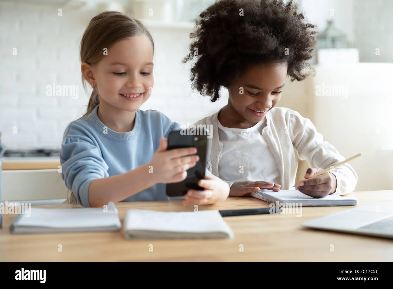 While african sister studying, another girl having fun using smartphone Stock Photo
