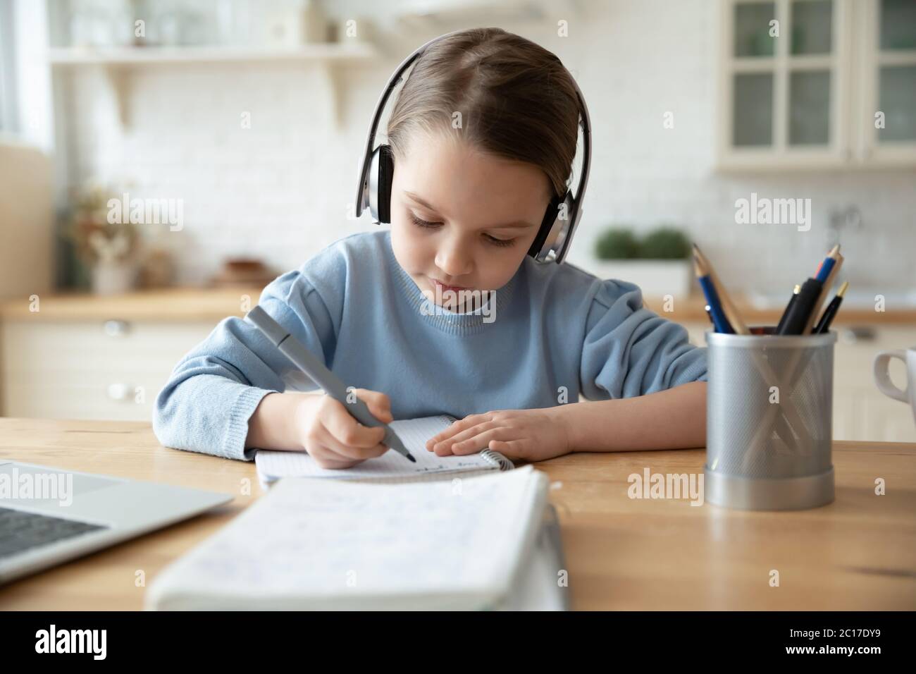 Girl in headphones learning at home doing homework using laptop Stock ...
