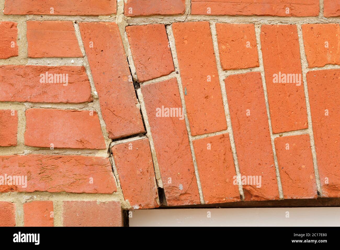 Dropping brick arch and cracking mortar in brickwork above a window in a UK house. Home maintenance and repairs Stock Photo