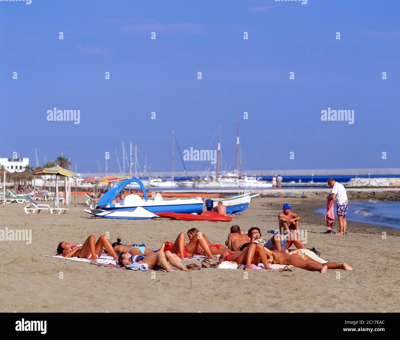 Group sunbathing on beach, Marbella, Costa del Sol, Malaga Province, Andalucia, Spain Stock Photo