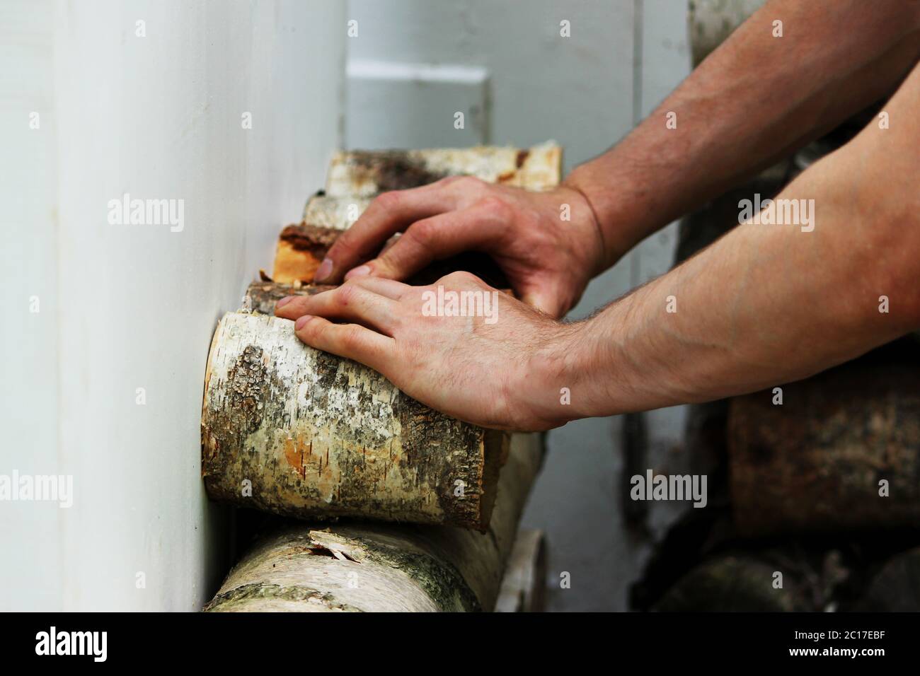 The worker restores a window in the historical building - a birch house of the Gatchina park, fastening pieces of birch with a s Stock Photo