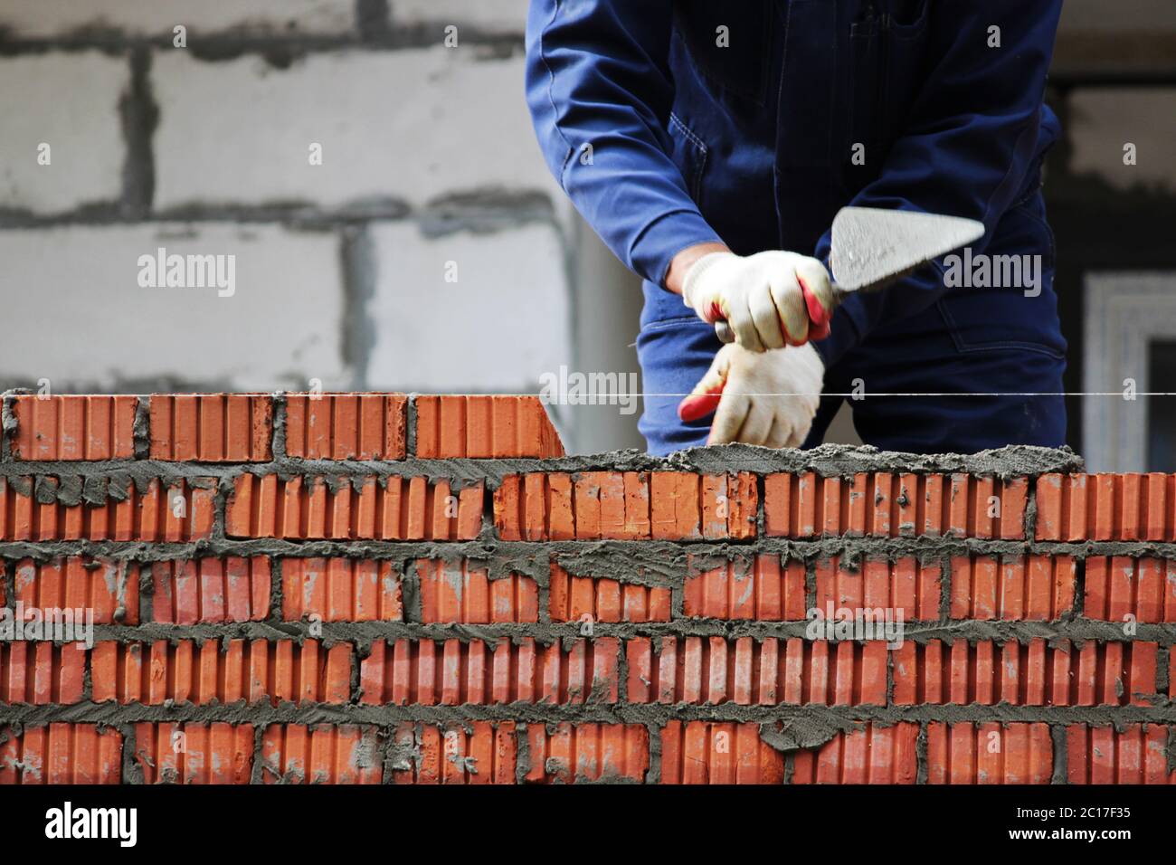 professional construction worker laying bricks and building house on industrial site. Stock Photo
