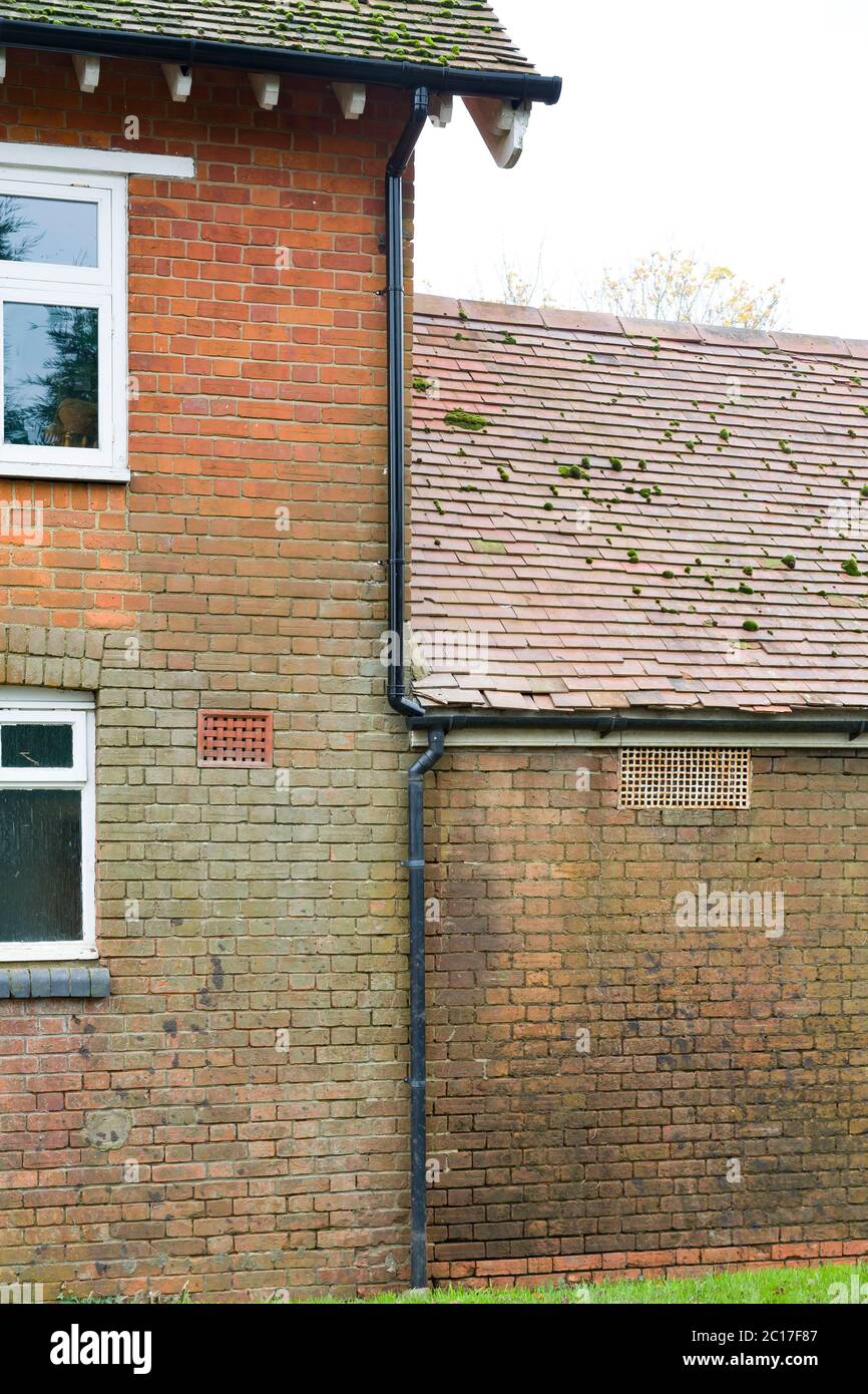 Water damage, damp and staining on a brick wall due to leaking damaged and overflowing gutters and drainpipe, UK Stock Photo