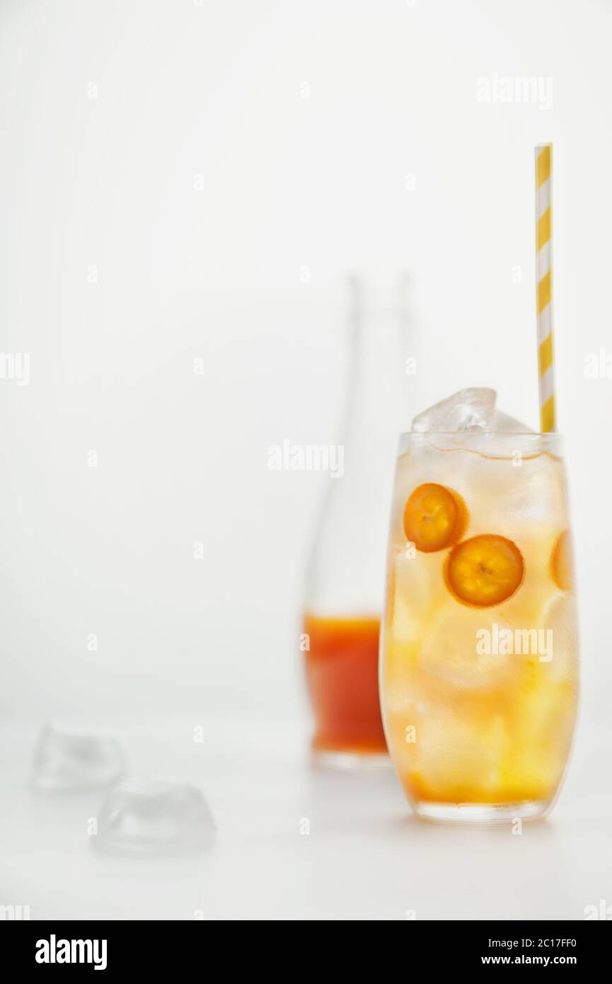 Summer citrus drink with oranges and  kumquats  and ice cubes on white background. Summer refreshing drink. Image with  space for text. Stock Photo