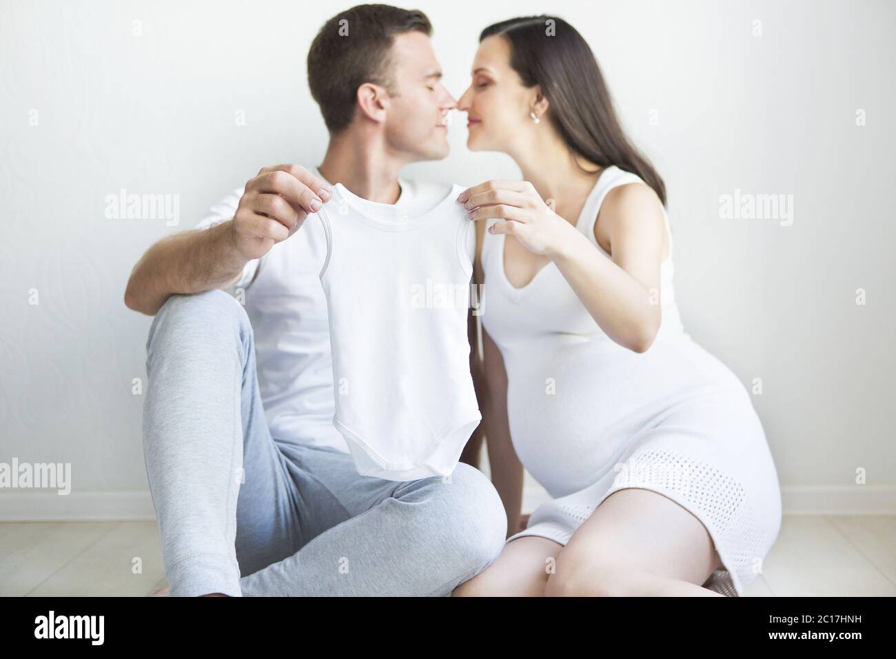 Young man and pretty pregnant woman with baby wear Stock Photo - Alamy