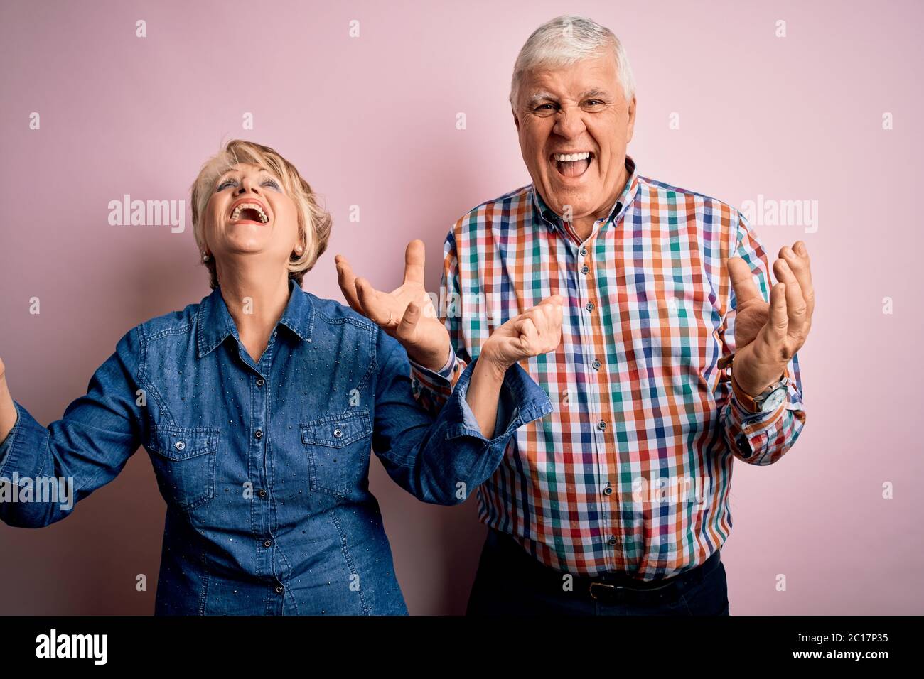 Senior beautiful couple standing together over isolated pink background ...