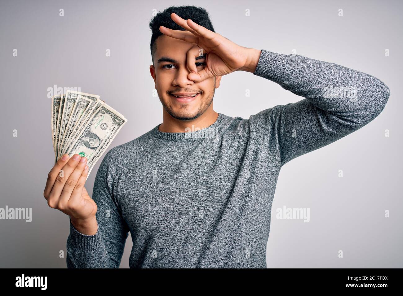 Young handsome man holding bunch of dollars banknotes over isolated ...
