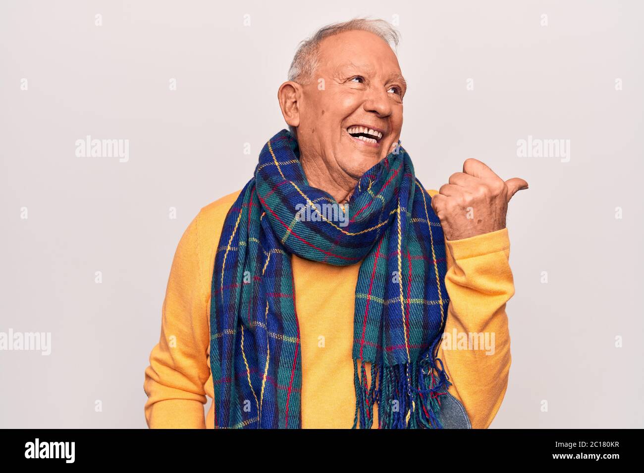 Senior handsome grey-haired man wearing casual scarf over isolated white  background pointing thumb up to the side smiling happy with open mouth  Stock Photo - Alamy
