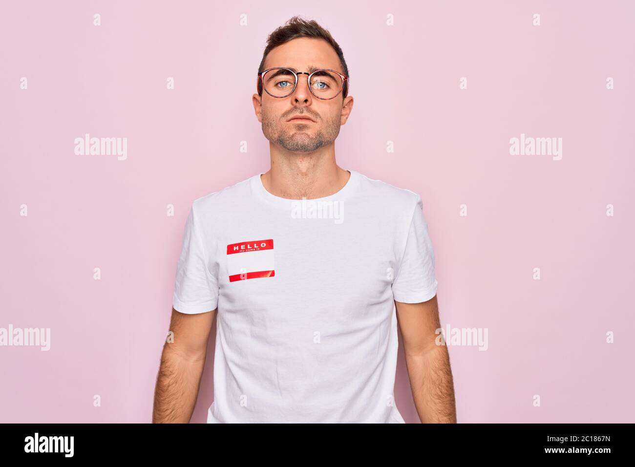 Handsome man with blue eyes wearing sticker with hello my name is ...