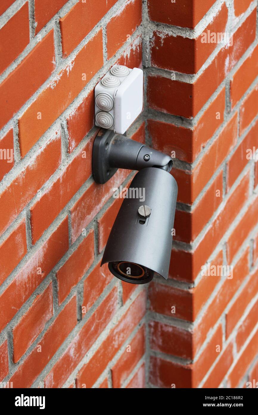 A video camera on a red brick wall protects the territory from the invasion of strangers. Stock Photo
