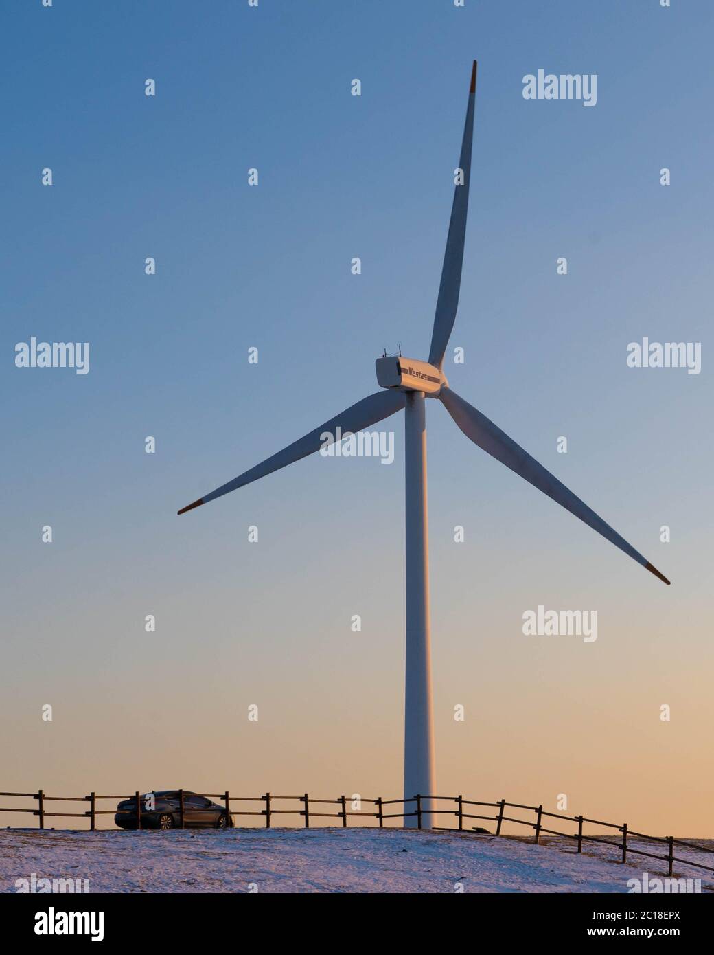 Wind turbine on the hill with a car on a golden hour sunset Stock Photo