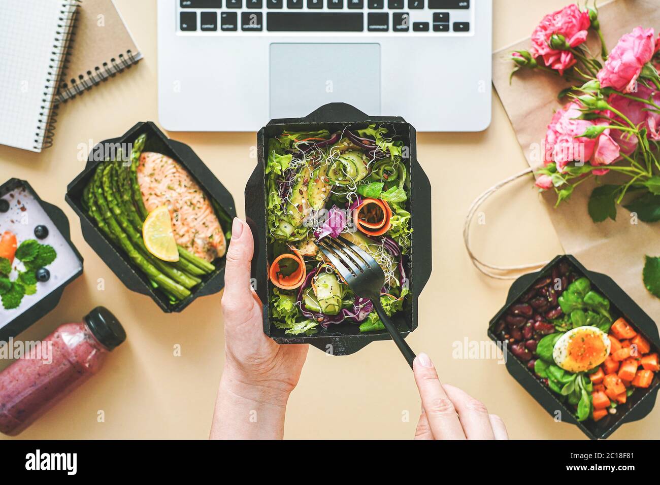 Female hands hold food delivery box having lunch at work from home office. Stock Photo