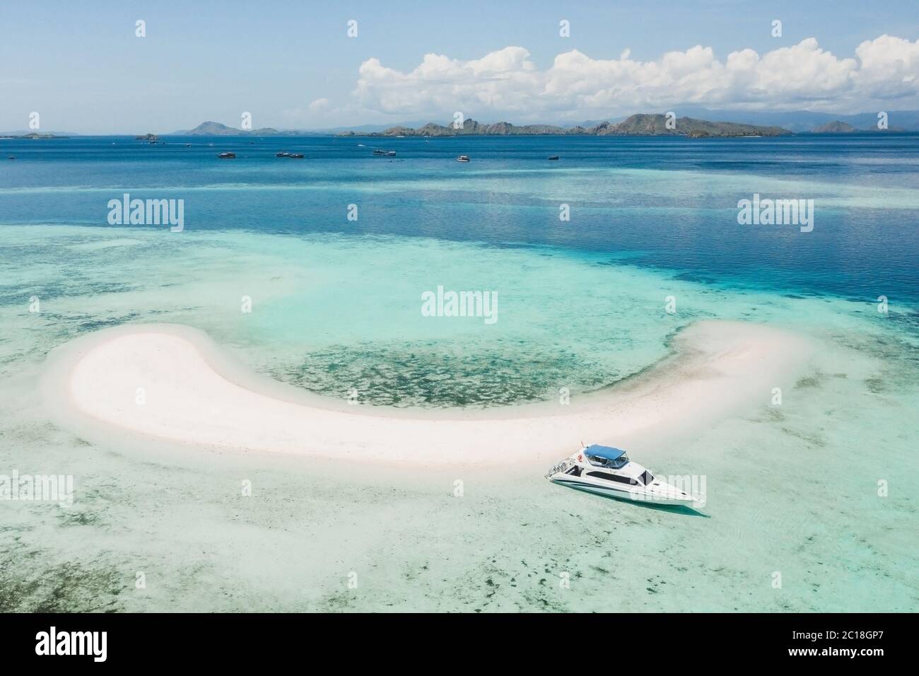 Aerial view of Taka Makassar island in Komodo national park, Indonesia. Empty paradise small white sand island on coral reef. Luxury boat near beach. Stock Photo