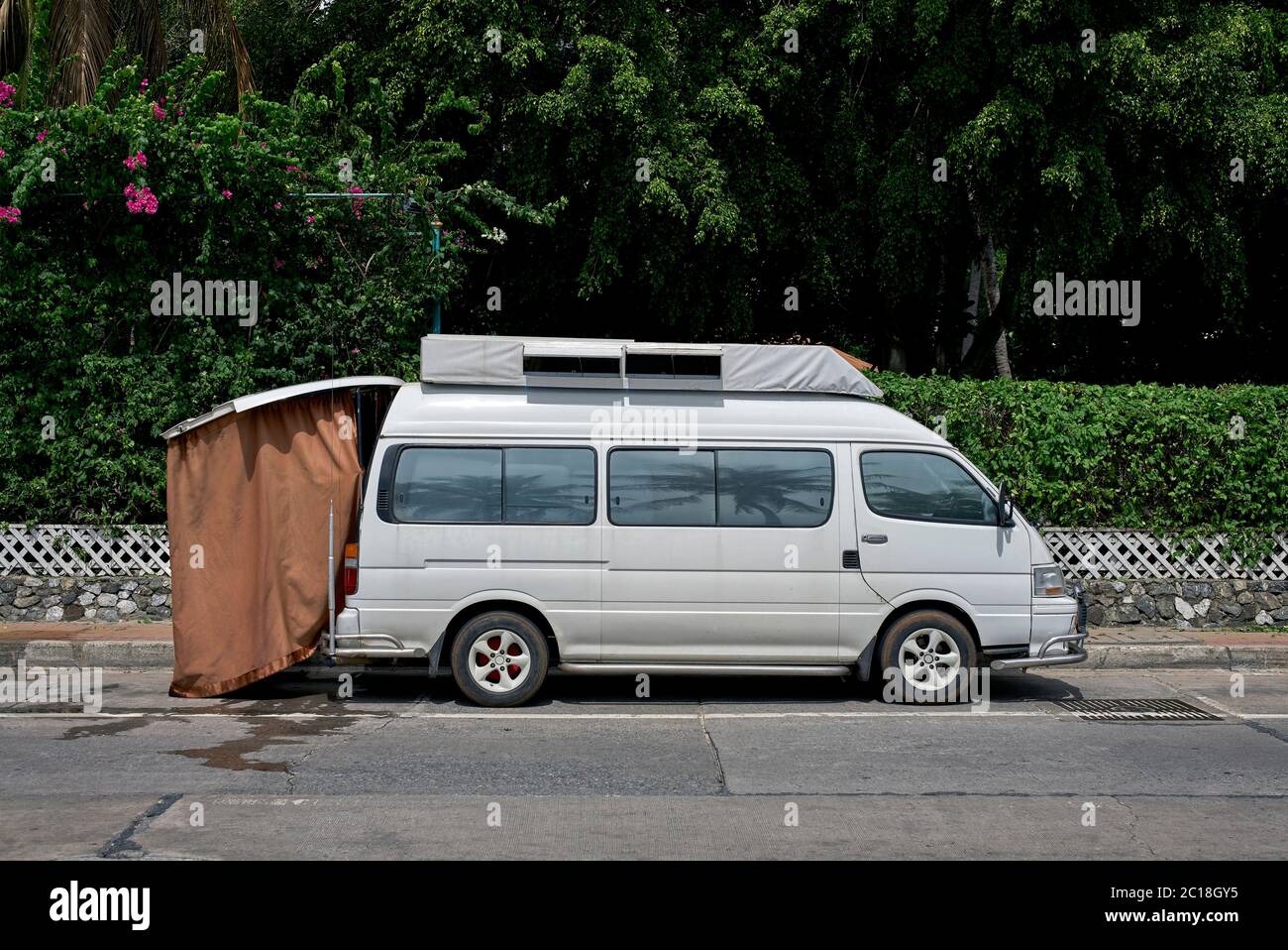 Caravanette, or camper van, with rear fitted shower curtain parked on the street clearly recently used. Thailand Southeast asia Stock Photo