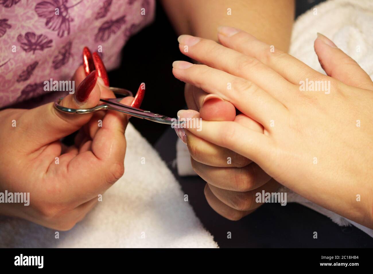 manicurist at the training courses of a manicure prepares the hand of a lady client with a manicure scissors for cuticles before Stock Photo