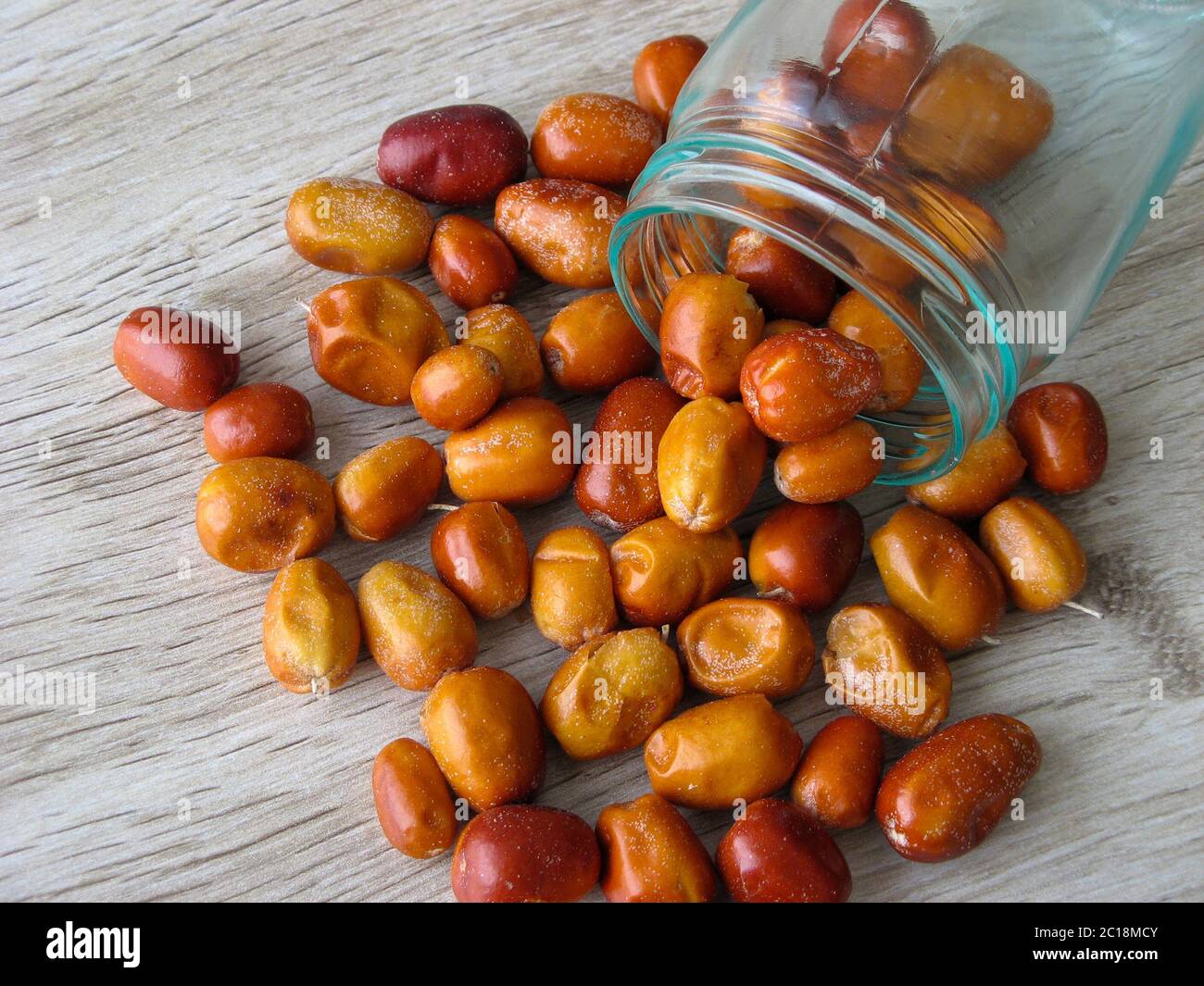 Organic dried fruit of Oleaster scattered from a glass bottle on wooden table. Fresh fruit of the Oleaster, Silver berry,Persian olive,   or wild oliv Stock Photo