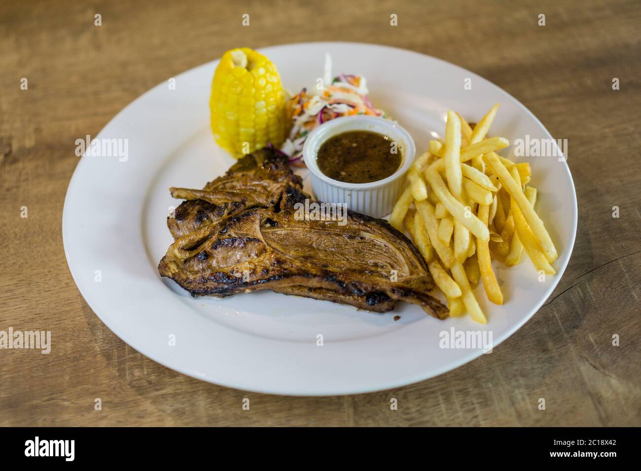 Juicy lamb chop grill to perfection with barbeque sauce, french fries, corn and coleslaw as side