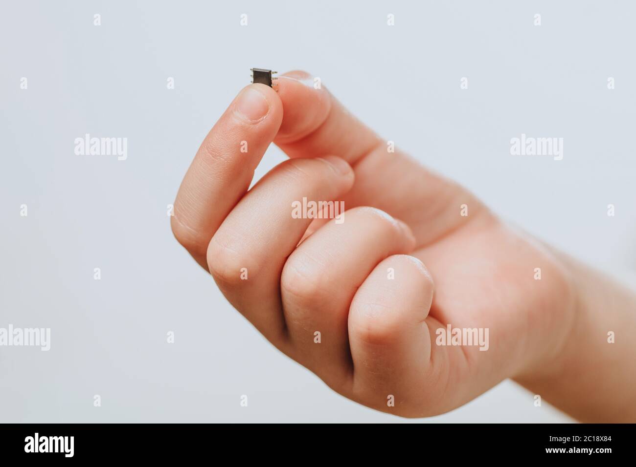 A small black chip holds a children's hand. Chipization of people after an epidemic coronavirus.  Stock Photo