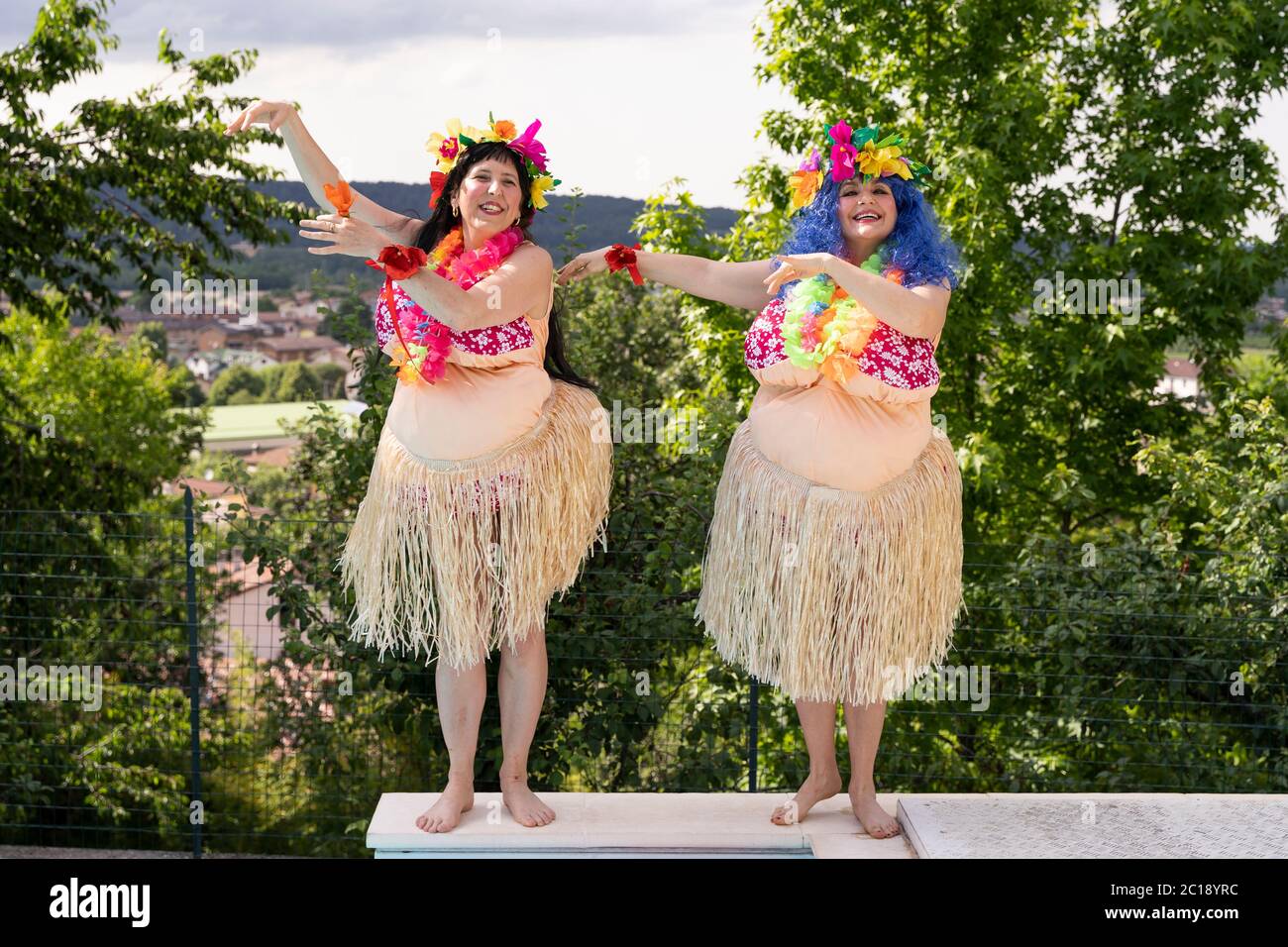 two female friends dressed in a Hawaiian costume have fun dancing by the  pool Stock Photo - Alamy