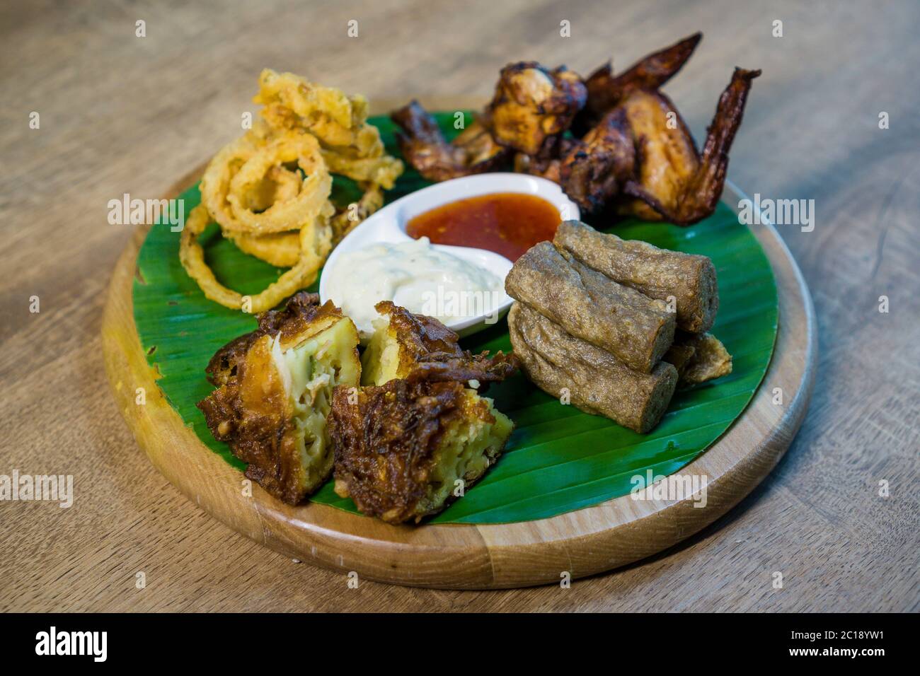 Food platter consist of smoked chicken wing, onion rings, keropok lekor or fried fish snack and fried prawn fritters. Stock Photo