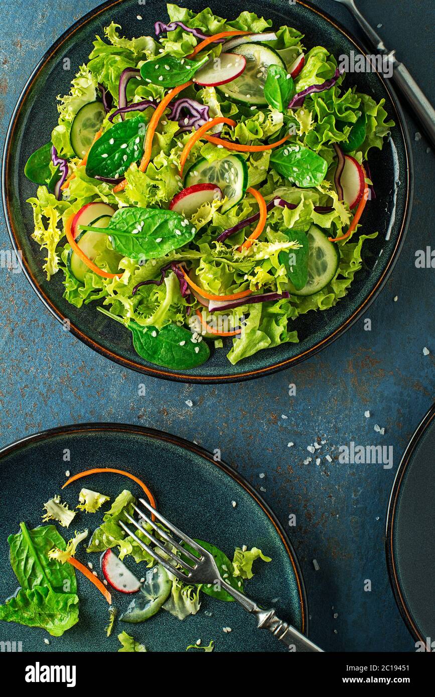 Green lettuce salad meal with fresh mixed vegetables on blue table background Stock Photo