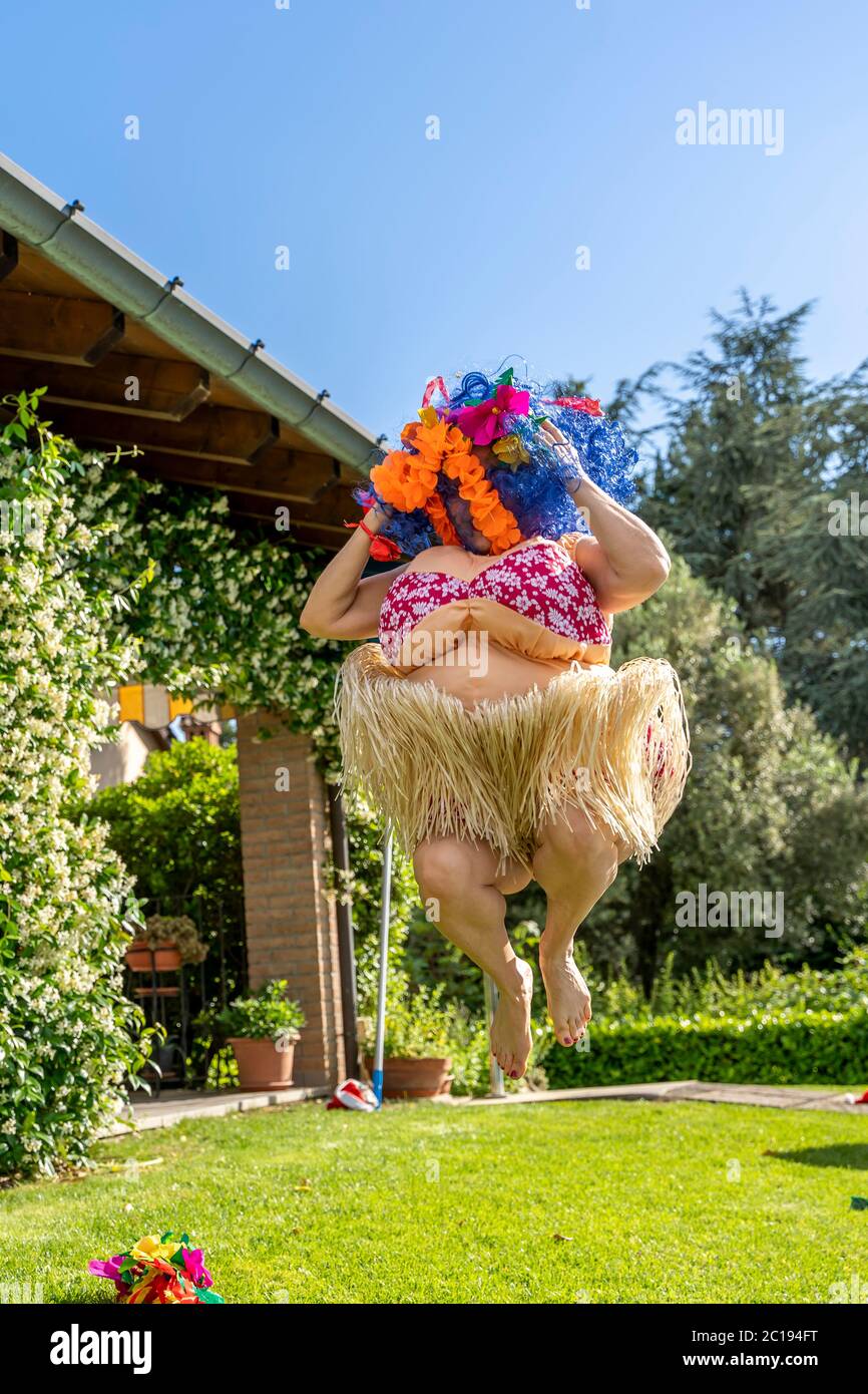 athletic woman dressed in fat Hawaiian costume is jumping upwards by the swimming pool Stock