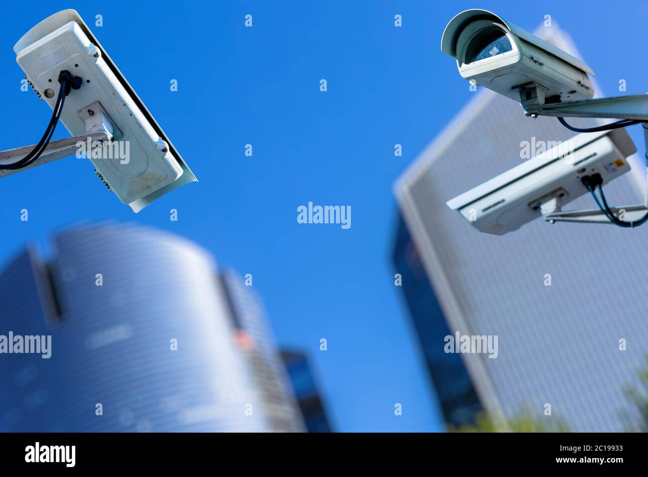 two cctv security camera in a city with blury business building on background Stock Photo