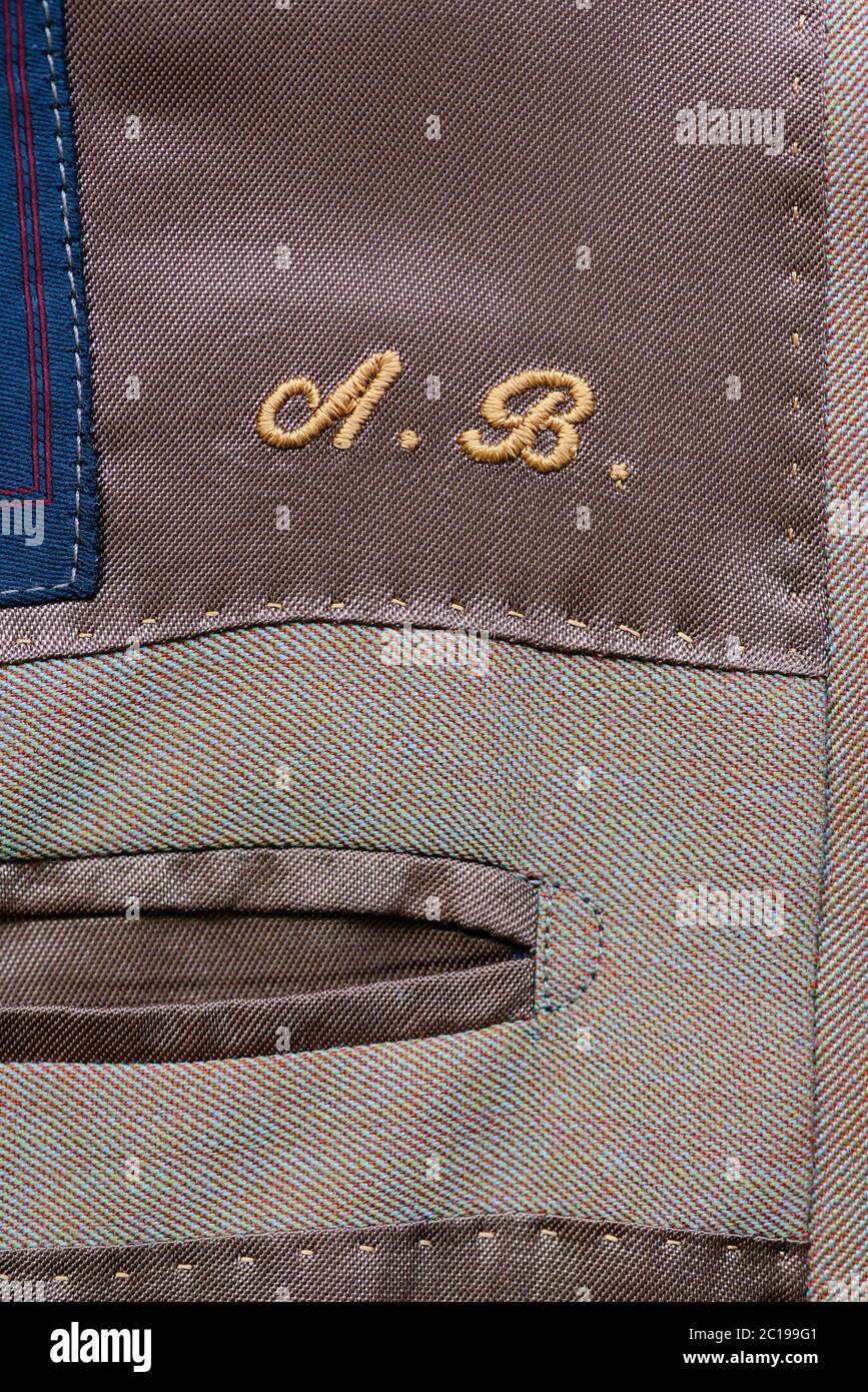 Initials embroidered inside a bespoke garment in yellow thread above an inside pocket in close up on the textile Stock Photo