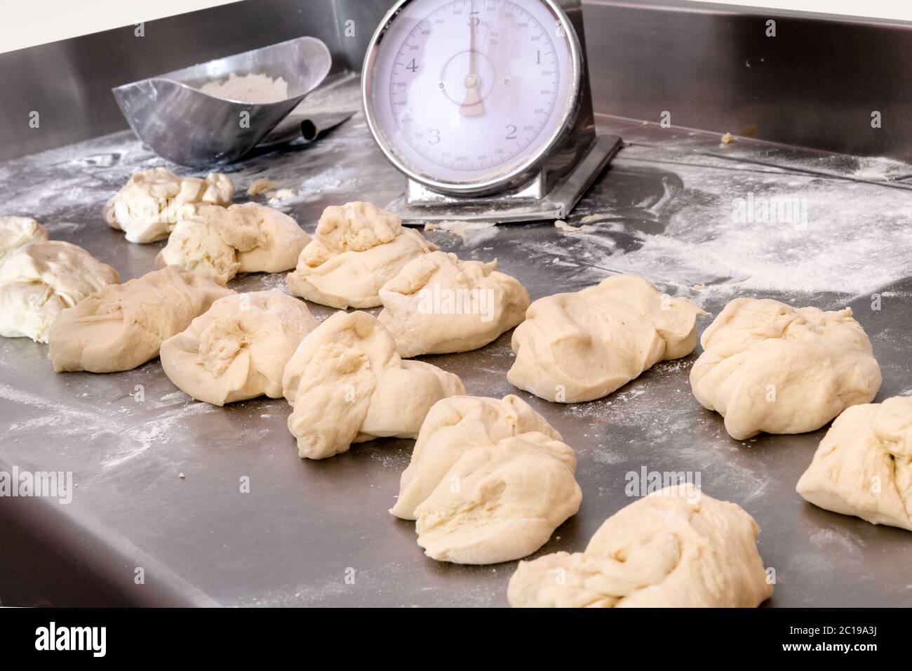 Single portions of pizza dough on a floured kitchen counter with a scale for weighing in a pizzeria or restaurant during preparation of traditional It Stock Photo