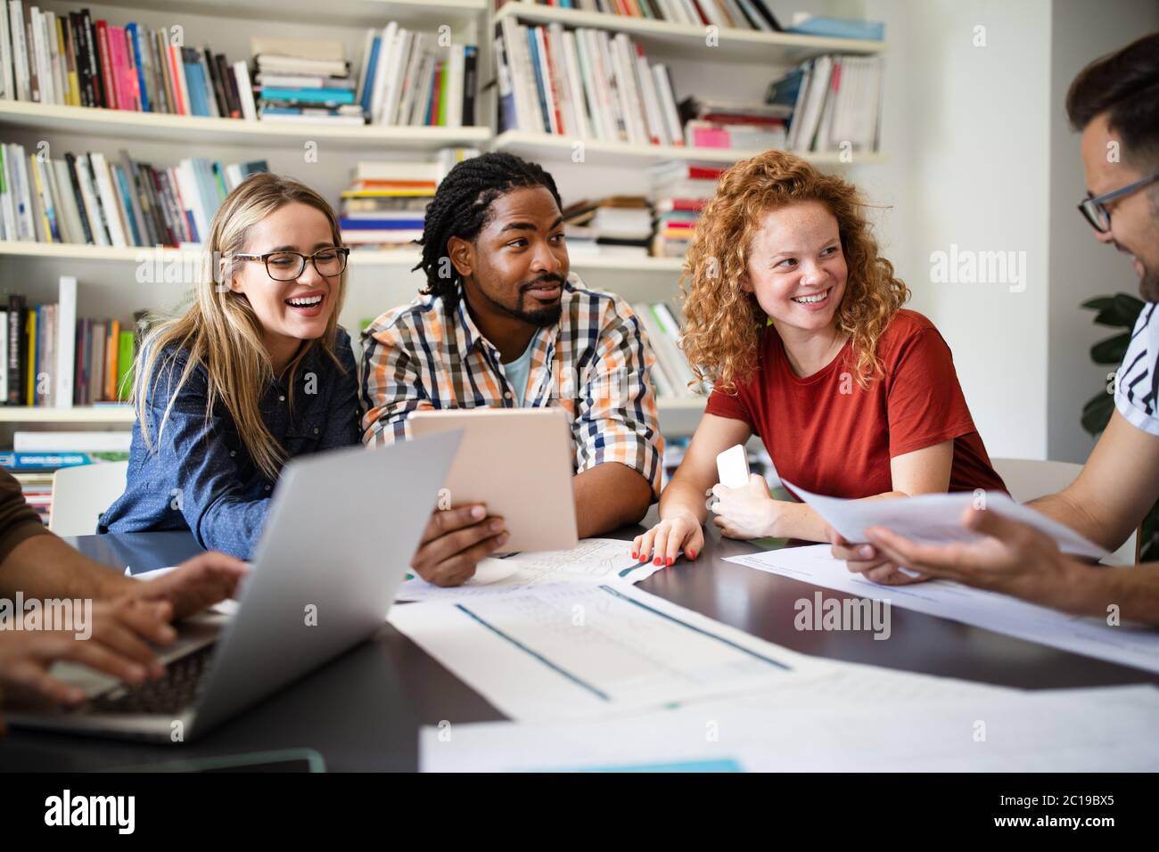 Young architect colleagues are analyzing blueprints while working on a new project Stock Photo