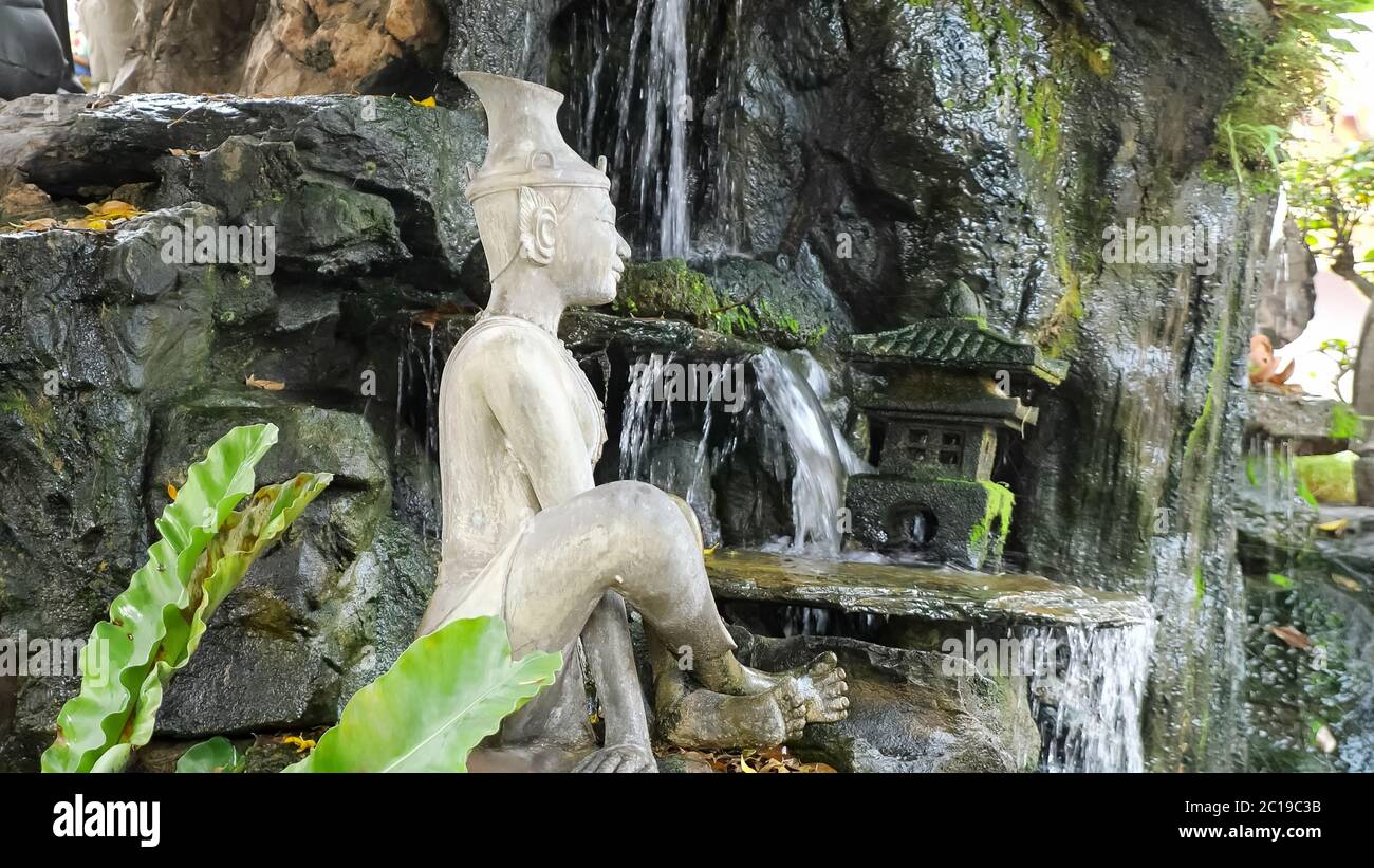 beautiful white stone meditating Buddha statue located near artificial