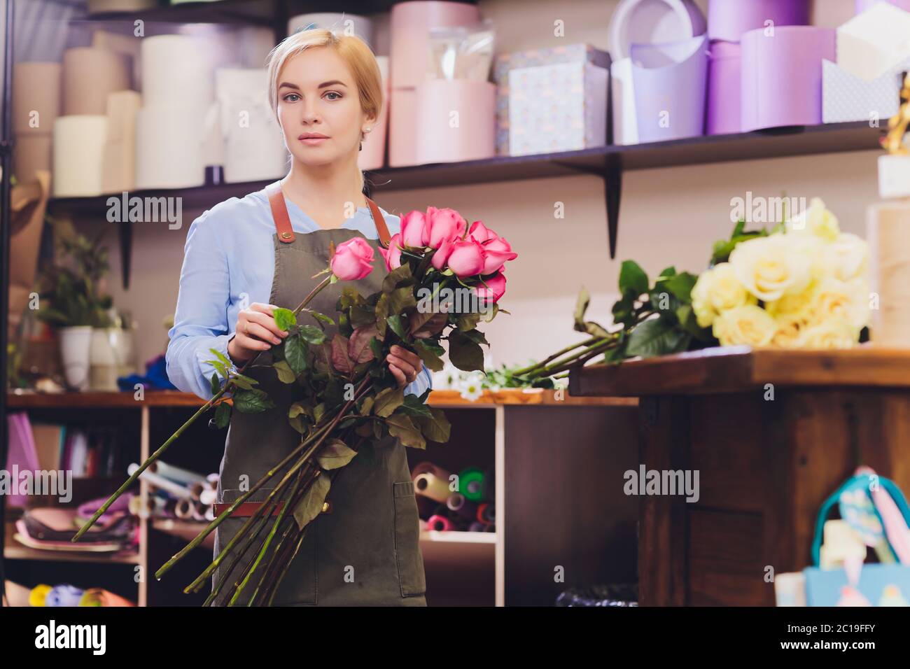 Female sales assistant working as florist and holding bouquet with